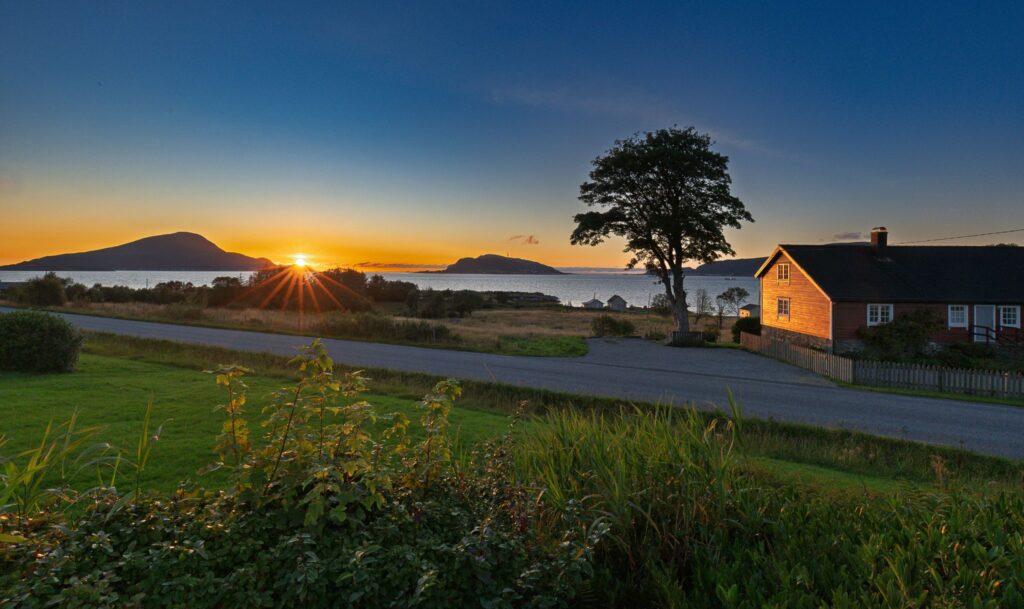 Solnedgang over Hildre på Sunnmøre med hus, sjø og fjell